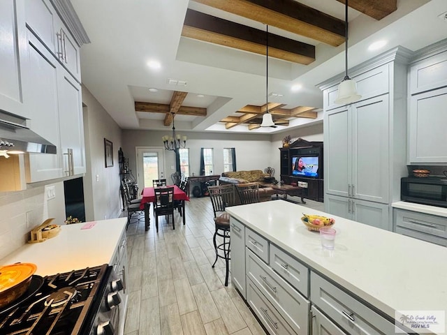 kitchen featuring stainless steel gas range, hanging light fixtures, light wood-type flooring, gray cabinets, and beamed ceiling