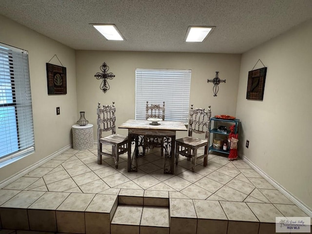 dining room featuring baseboards, a textured ceiling, and light tile patterned floors