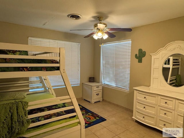 bedroom with light tile patterned flooring, a ceiling fan, visible vents, and baseboards