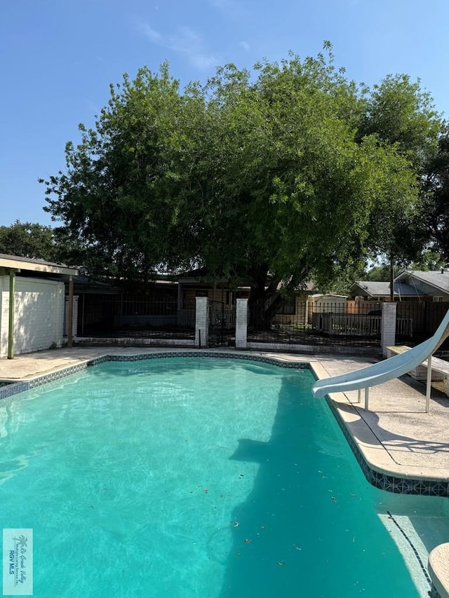 view of swimming pool featuring a fenced in pool, a water slide, and fence