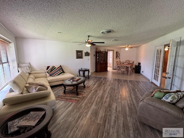 living room featuring a ceiling fan, a textured ceiling, french doors, and wood finished floors