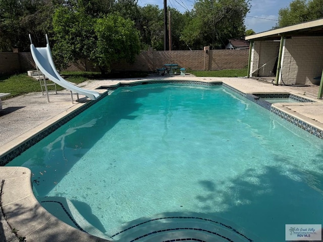 view of pool featuring an in ground hot tub, a fenced in pool, a fenced backyard, a patio, and a water slide