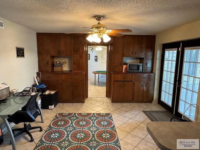 interior space featuring a textured ceiling, stainless steel microwave, a healthy amount of sunlight, and ceiling fan