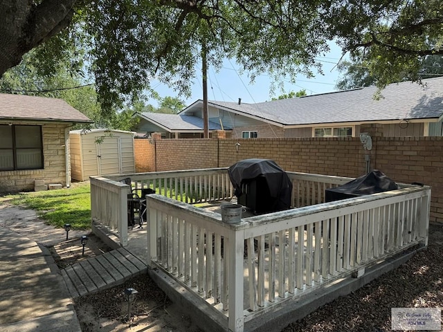 wooden terrace with an outdoor structure, a fenced backyard, a shed, and a grill