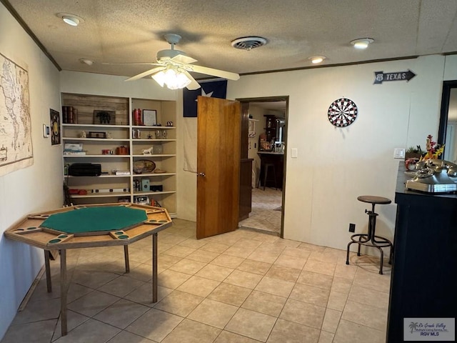 recreation room with a ceiling fan, a textured ceiling, visible vents, and light tile patterned floors