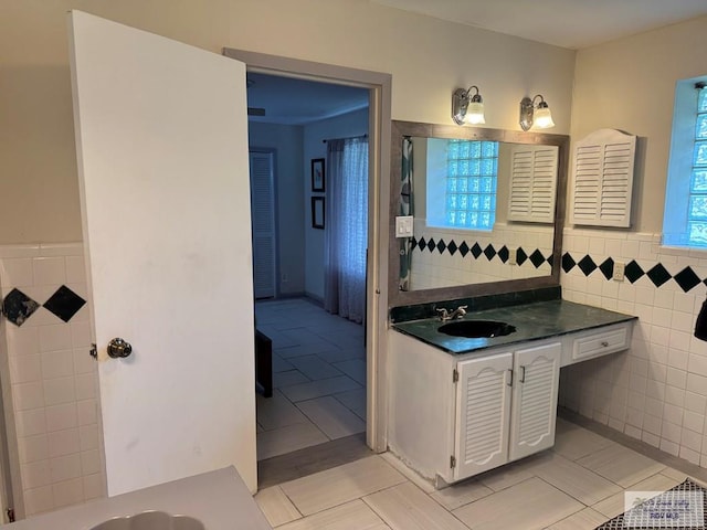 bathroom with tile walls, wainscoting, tile patterned flooring, and vanity