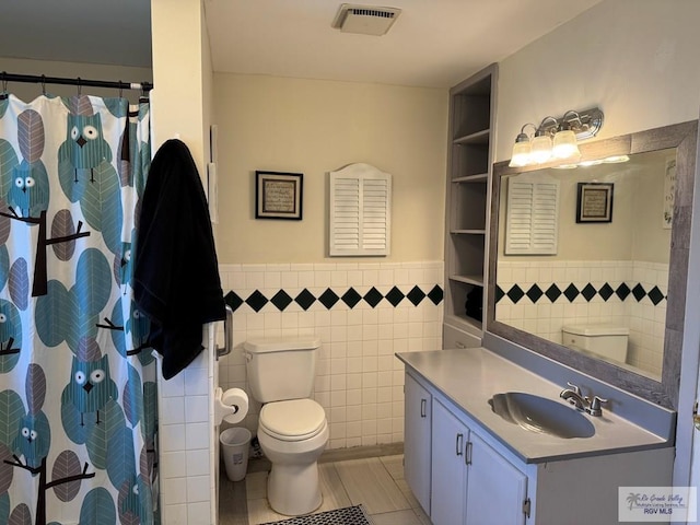 bathroom with visible vents, tile walls, tile patterned flooring, a wainscoted wall, and toilet