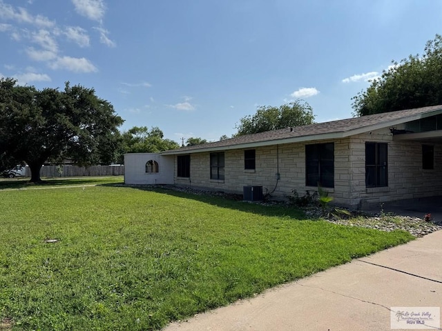 exterior space featuring a lawn, fence, and stone siding