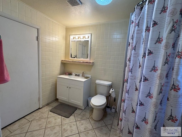 bathroom featuring visible vents, tile patterned flooring, toilet, and tile walls
