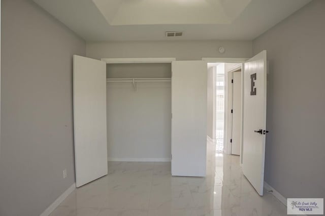 7549 Laurel Ave, Brownsville, TX 78526 - unfurnished bedroom with light marble finish flooring, a closet, and a tray ceiling