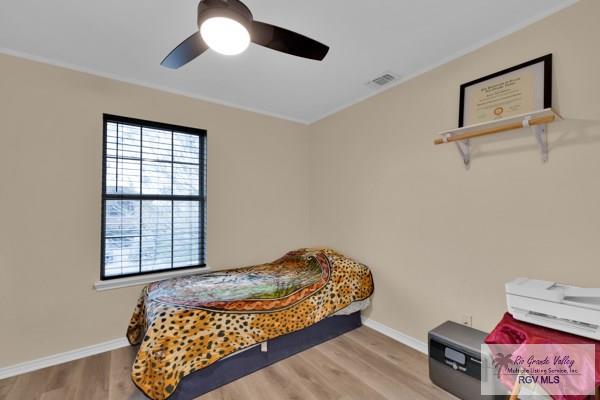 bedroom featuring ceiling fan, light wood-type flooring, visible vents, and baseboards