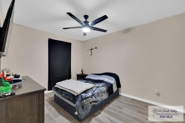 bedroom featuring ceiling fan, baseboards, and wood finished floors