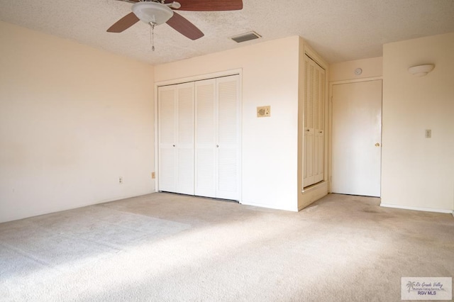 unfurnished bedroom with light carpet, ceiling fan, a textured ceiling, and visible vents