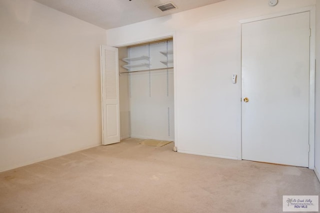 unfurnished bedroom featuring light carpet, visible vents, and a closet