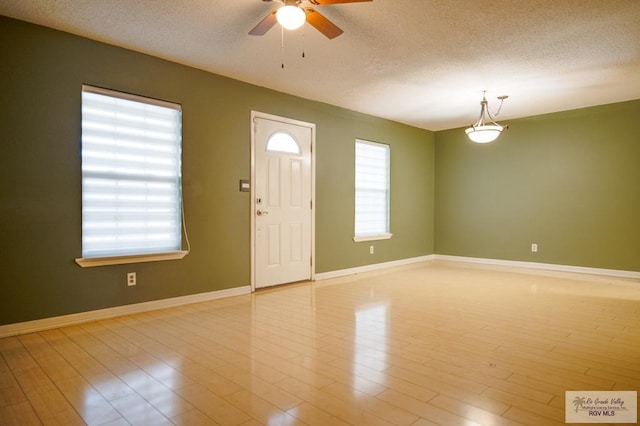 foyer featuring light wood-style floors, baseboards, and a textured ceiling