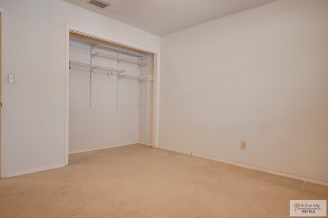 unfurnished bedroom with light colored carpet and a closet