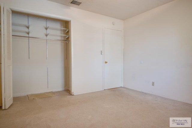 unfurnished bedroom featuring a closet, light carpet, and visible vents