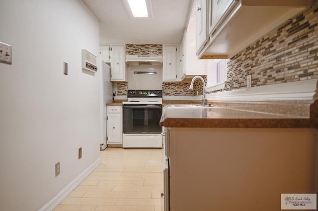 kitchen featuring white range with electric cooktop, decorative backsplash, white cabinets, freestanding refrigerator, and a sink