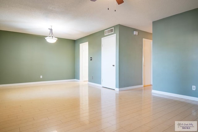 unfurnished room featuring light wood finished floors, a textured ceiling, baseboards, and a ceiling fan