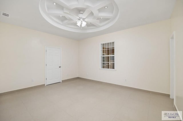 tiled empty room featuring a tray ceiling, ceiling fan, and coffered ceiling