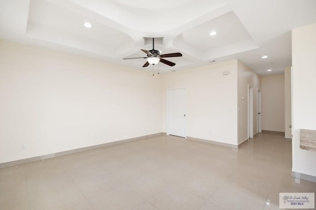 spare room with a tray ceiling and ceiling fan