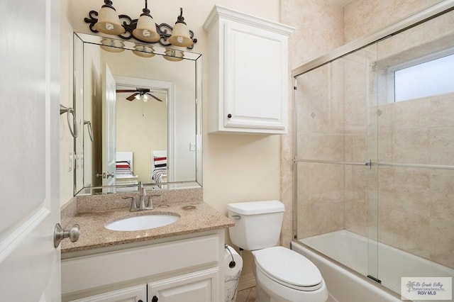 full bathroom featuring ceiling fan, vanity, bath / shower combo with glass door, and toilet