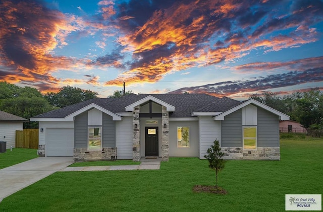 view of front of property with a garage, a yard, and central air condition unit