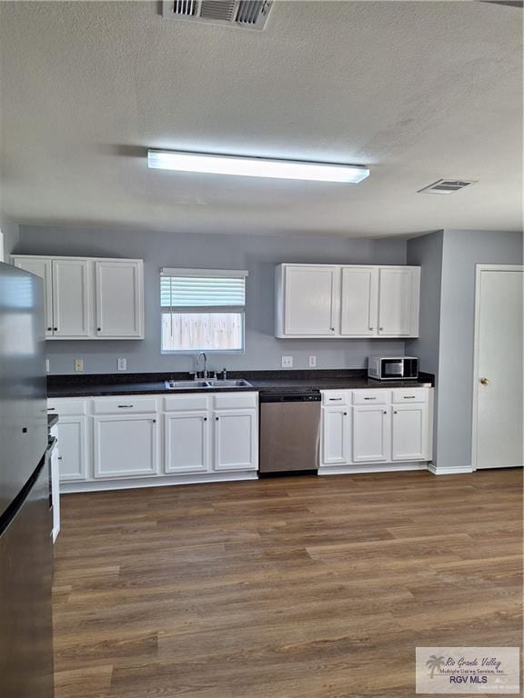 kitchen featuring a textured ceiling, stainless steel appliances, sink, white cabinets, and dark hardwood / wood-style floors