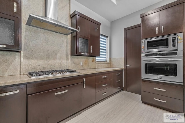 47 Medical St, Brownsville, TX 78520 - kitchen with stainless steel appliances, extractor fan, dark brown cabinetry, decorative backsplash, and light stone counters