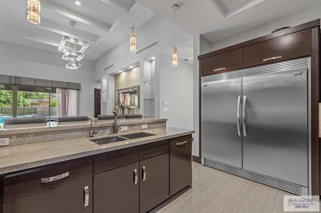 47 Medical St, Brownsville, TX 78520 - kitchen featuring built in refrigerator, a sink, dark brown cabinetry, hanging light fixtures, and beamed ceiling