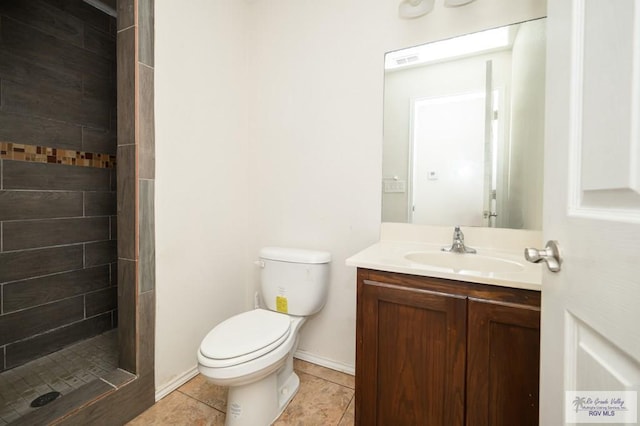 bathroom featuring tile patterned flooring, vanity, tiled shower, and toilet