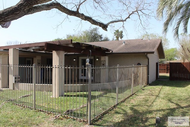 exterior space with a yard, a gate, fence, and brick siding