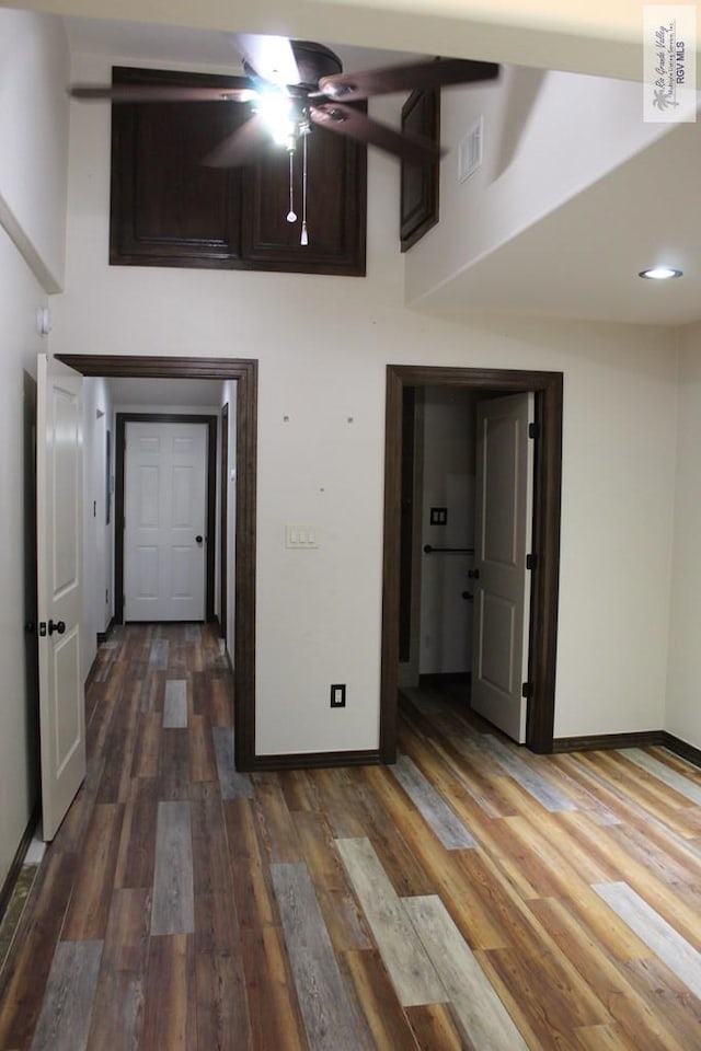 interior space with baseboards, a high ceiling, visible vents, and wood finished floors