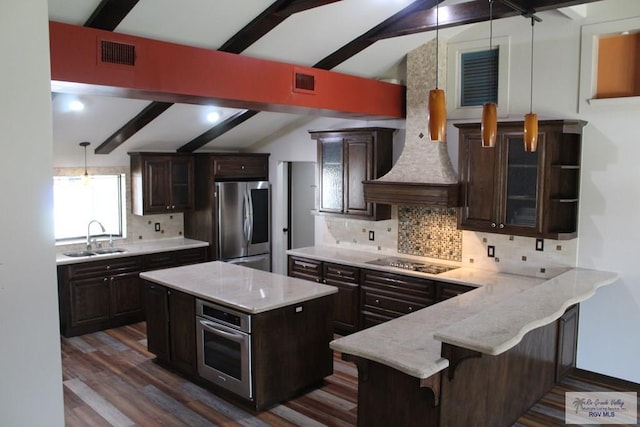 kitchen featuring pendant lighting, vaulted ceiling with beams, stainless steel appliances, tasteful backsplash, and a sink