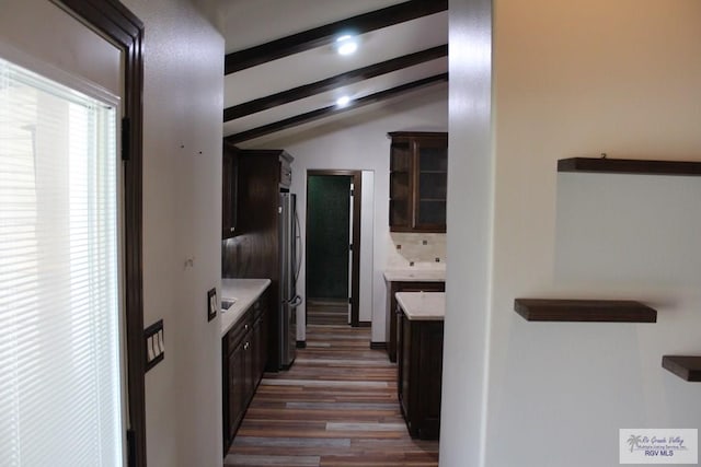 kitchen with vaulted ceiling with beams, light countertops, backsplash, freestanding refrigerator, and dark brown cabinets