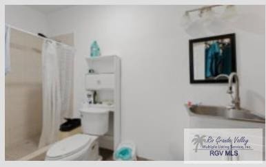 bathroom with a shower with shower curtain, toilet, and sink