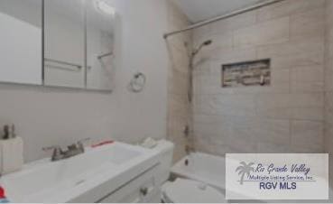 full bathroom with vanity, tiled shower / bath combo, and toilet