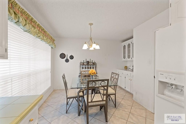 tiled dining space featuring a chandelier and a textured ceiling