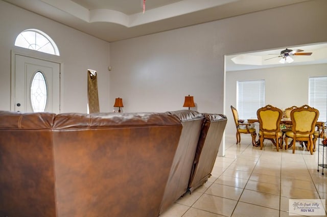 tiled living room featuring ceiling fan and a tray ceiling