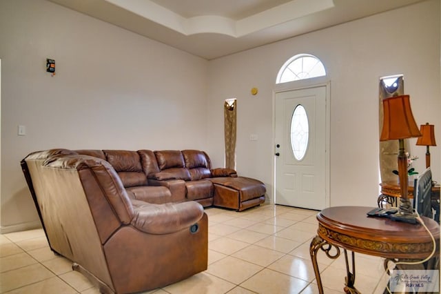 living room with a tray ceiling and light tile patterned flooring