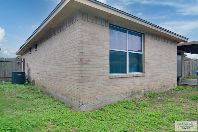 view of side of property featuring a yard and central AC