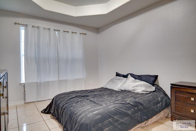 bedroom with light tile patterned floors and a tray ceiling