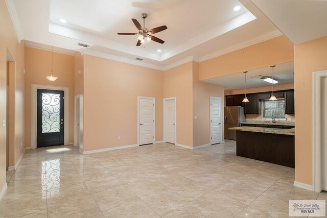 kitchen featuring a raised ceiling, stainless steel fridge, dark brown cabinets, and light stone countertops