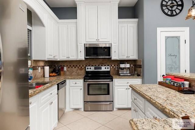 kitchen with backsplash, light stone countertops, white cabinets, and stainless steel appliances