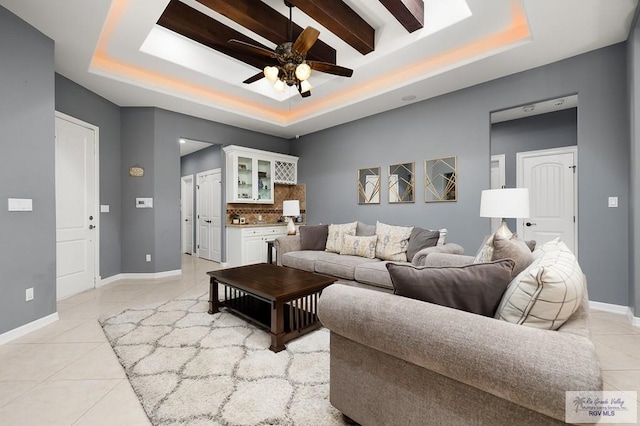 tiled living room with a tray ceiling and ceiling fan