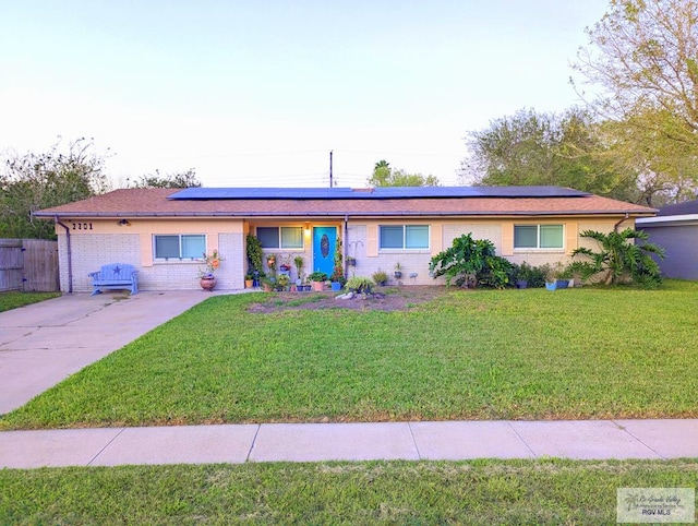 ranch-style home featuring a front lawn and solar panels