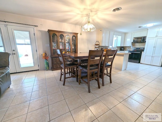 dining space featuring light tile patterned flooring and a notable chandelier