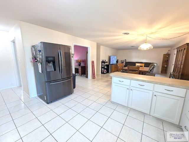 kitchen with fridge with ice dispenser, light tile patterned flooring, white cabinets, and hanging light fixtures