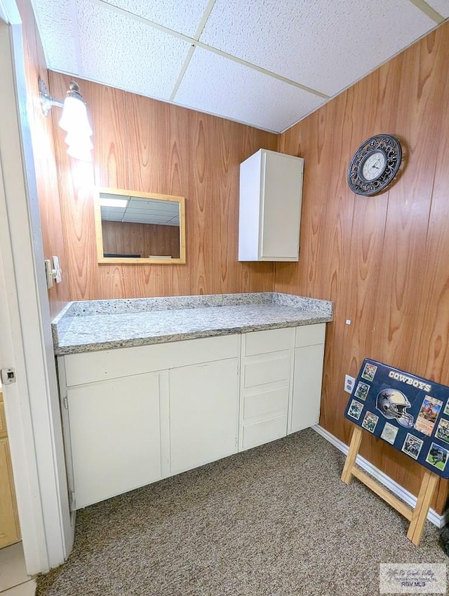 bathroom with a paneled ceiling and wood walls