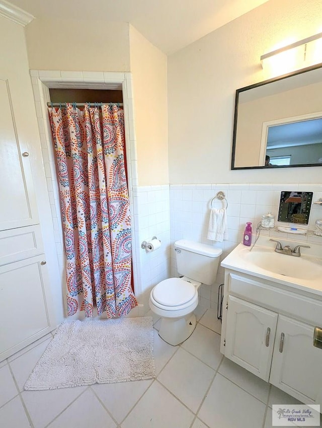 bathroom with vanity, tile patterned floors, toilet, tile walls, and curtained shower